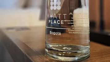 Una botella de vidrio transparente con la etiqueta 'HYATT PLACE' y la palabra 'Bogotá' sobre una superficie de madera.