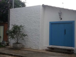 A white building with a blue door and a small tree in a planter.