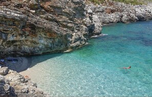 A rocky coastline with clear turquoise water, a swimmer, and a rocky beach. - 2 bedroom nice apartment in Olbia (Olbia)