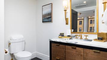 Une salle de bain avec des toilettes, un lavabo en marbre, des meubles en bois et un grand miroir.