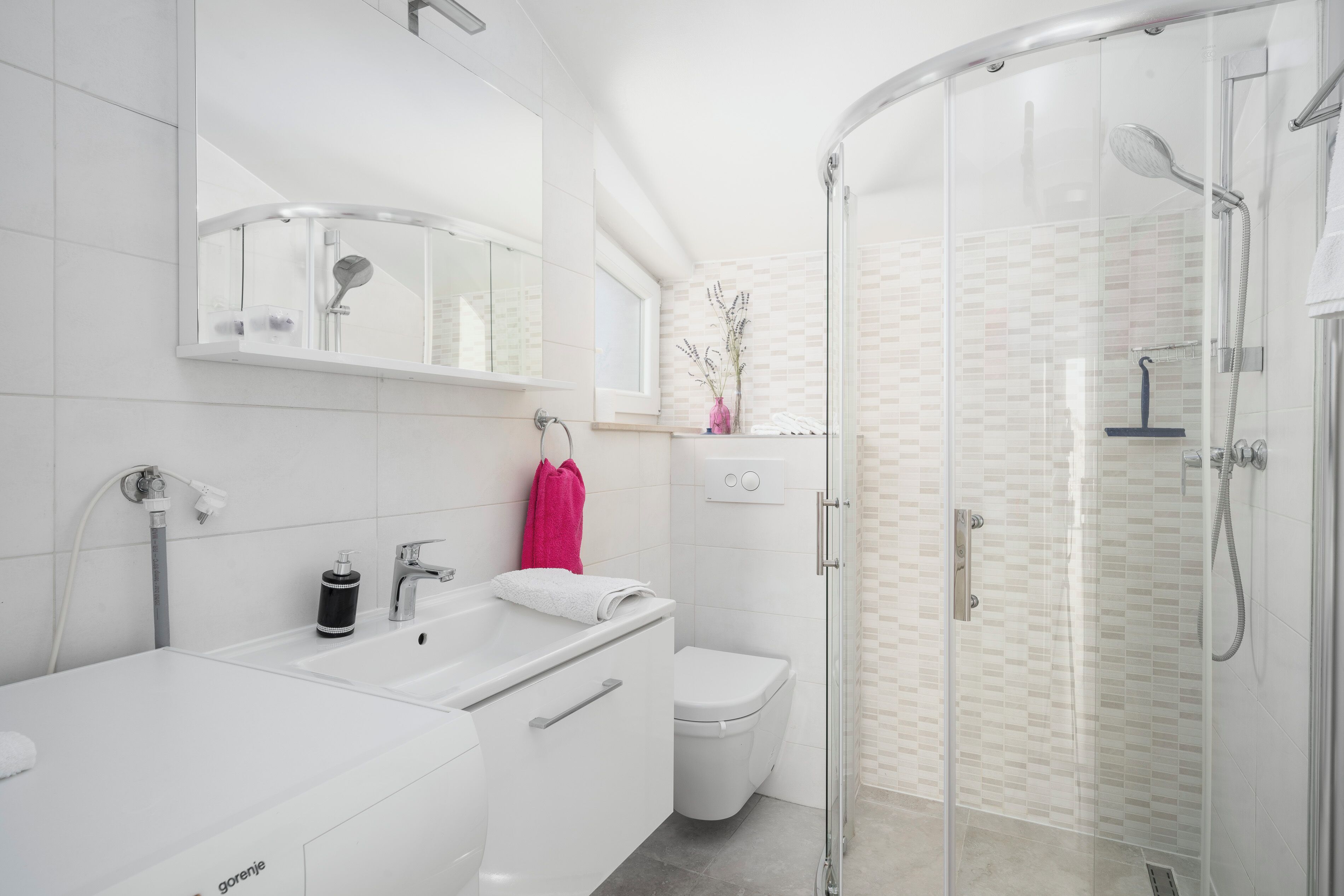 Un baño moderno con ducha acristalada, lavamanos blanco y retrete.