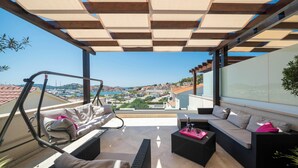 A balcony with a swing chair, a sofa, and a coffee table. - The Tribunj Suites (Tribunj)