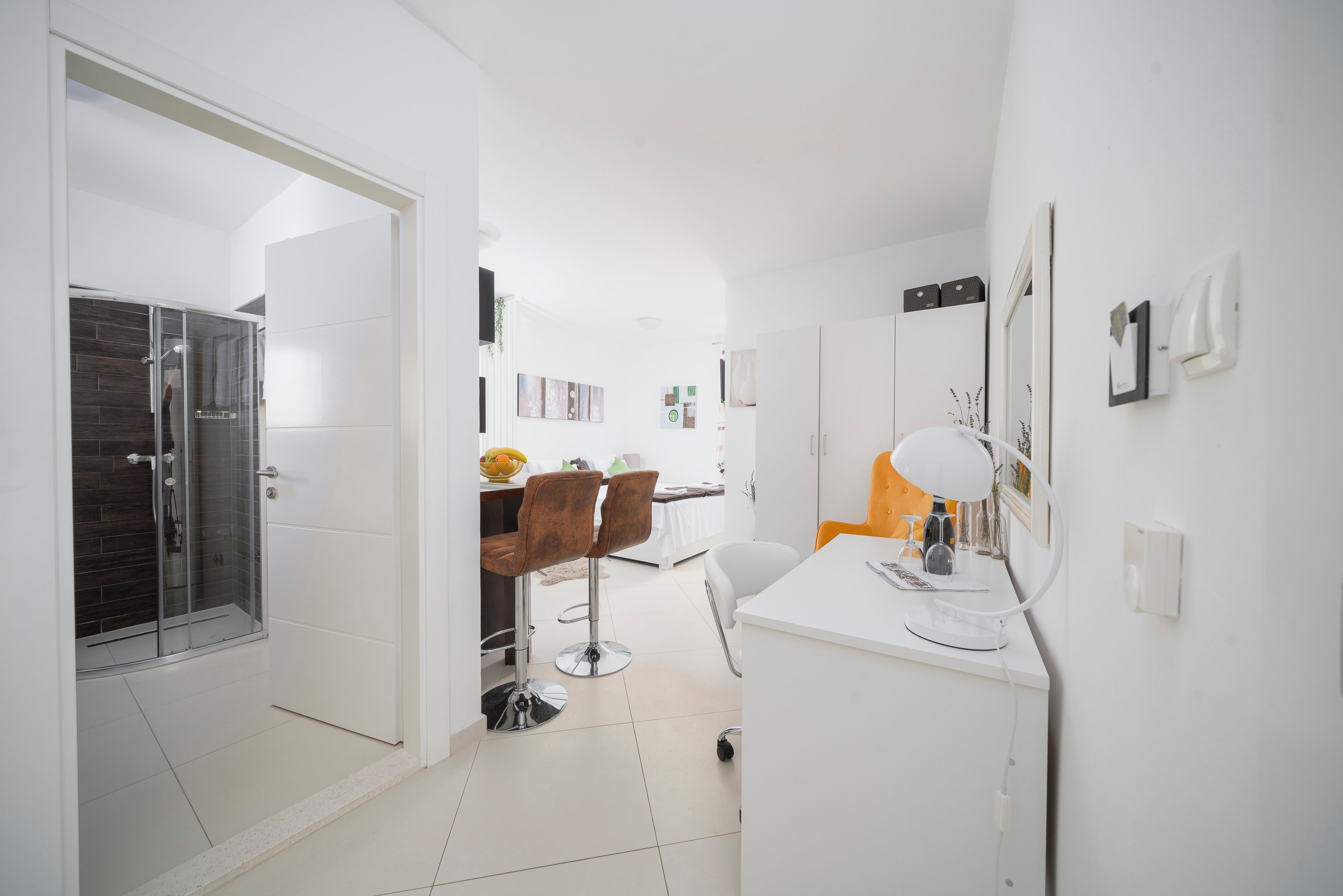 A modern kitchen with white cabinets, a white countertop, and a small island with a stool.