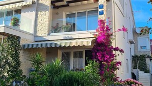 A two-story house with a balcony, stone facade, and a garden with various plants and flowers. - The Tribunj Suites (Tribunj)