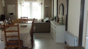 En spiseplads med et bord til fire, en sofa og et skab.