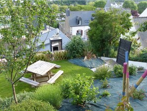 Enjoy a serene garden retreat surrounded by lush greenery and a wooden picnic table.