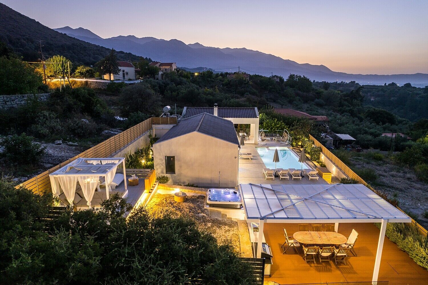 Una villa moderna con piscina, zona de estar exterior y vistas a las colinas circundantes.