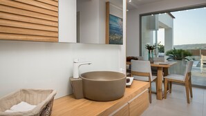 A modern bathroom with a wooden vanity, a large sink, and a view of the outdoors.