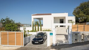 A modern building with a car parked in front, a staircase leading to the entrance, and a clear blue sky in the background.