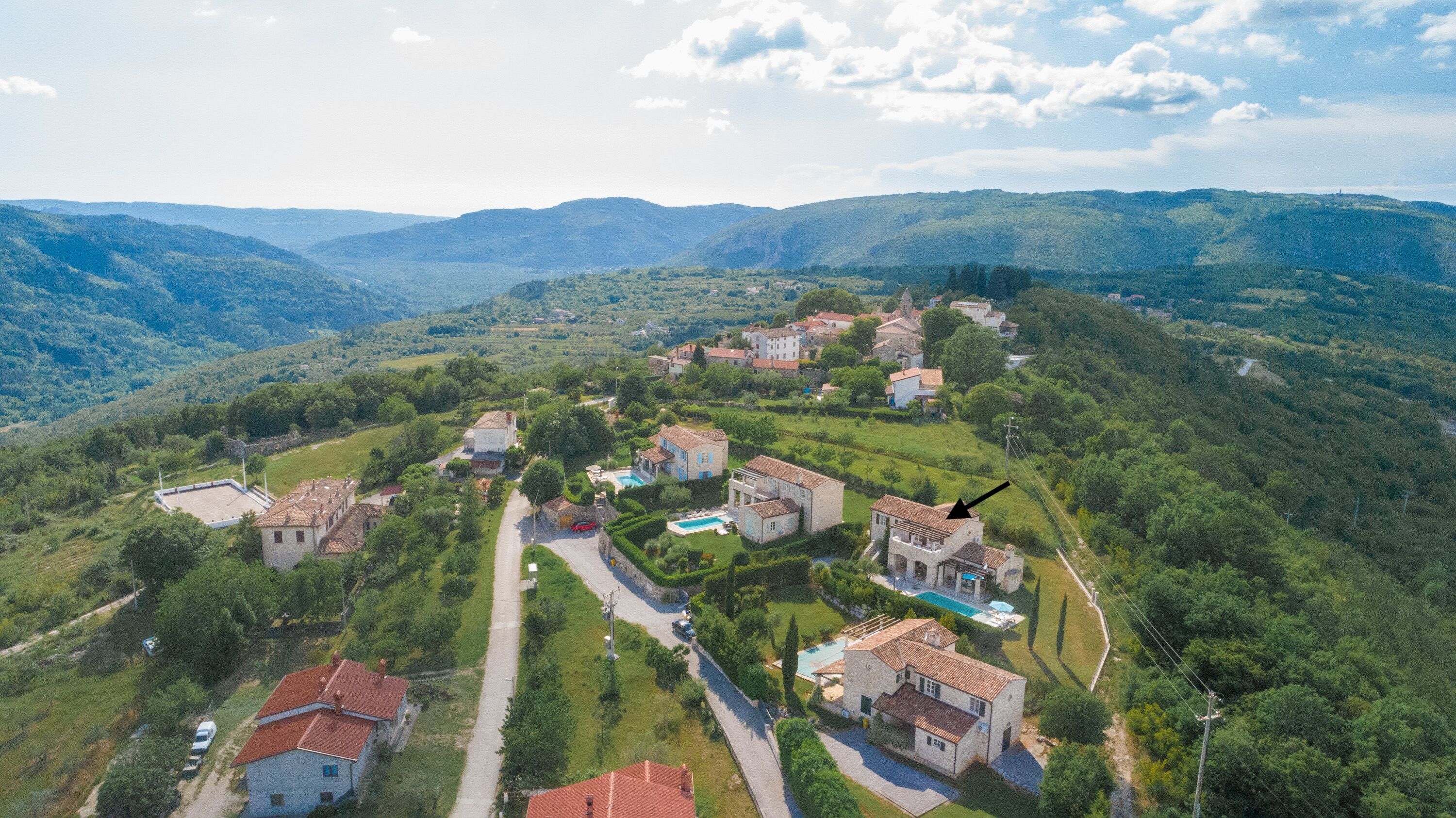 Vue aérienne d’un village avec des maisons, une piscine et une église.