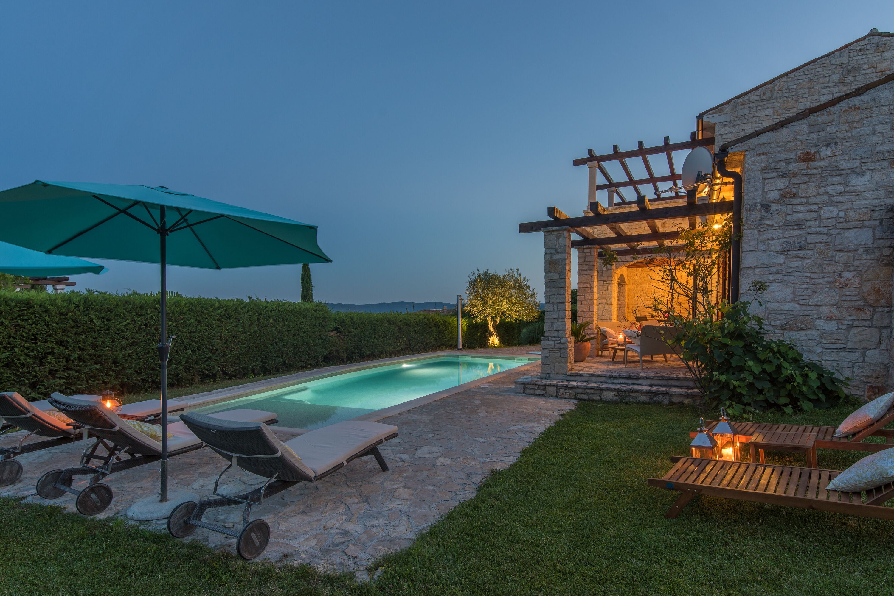 Ein Poolbereich mit Liegestühlen, einer Pergola und einem Steinhaus.