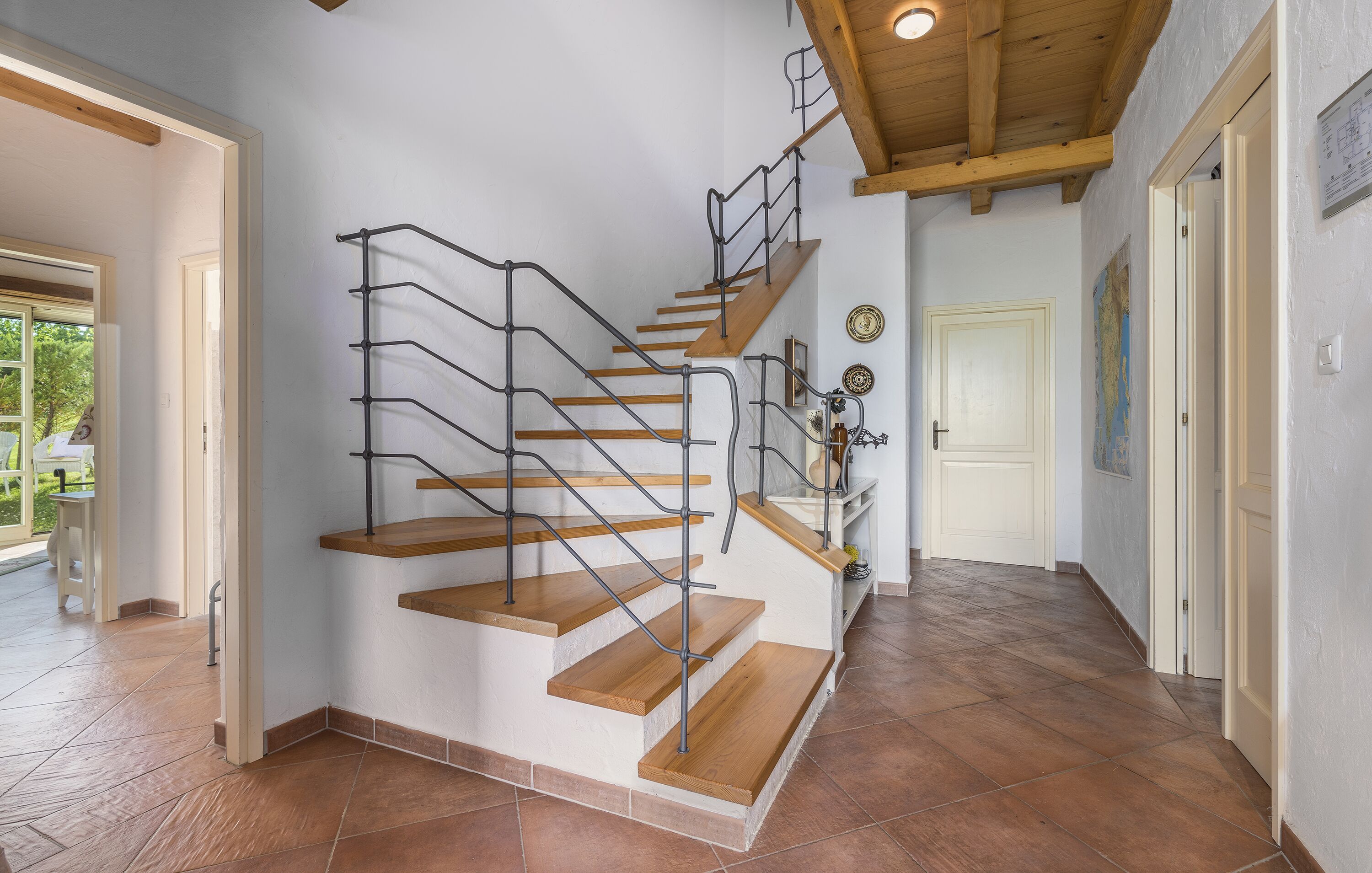 Eine Wendeltreppe mit Holzboden und Metallgeländern, die zu einem Zwischenpodest mit einer weißen Tür und einer Karte an der Wand führt.