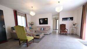 A spacious living room with a green armchair, a beige sofa, and a striped armchair. There are two chandeliers, a painting on the wall, and a vase with flowers on a side table. - Vacation rental L'ISLE SUR LA SORGUE LS2-331 (L´Isle sur la Sorgue)