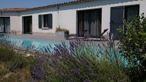 A pool area with a white building, outdoor seating, and lavender plants. - Vacation rental L'ISLE SUR LA SORGUE LS2-331 (L´Isle sur la Sorgue)