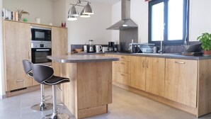 A modern kitchen with wooden cabinets, a central island, bar stools, and stainless steel appliances. - Vacation rental L'ISLE SUR LA SORGUE LS2-331 (L´Isle sur la Sorgue)