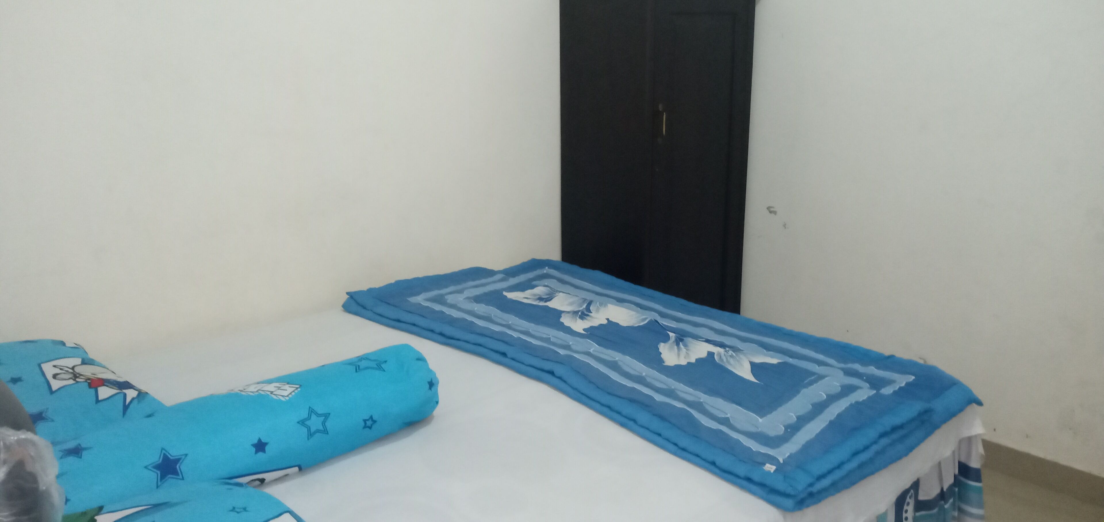 A single bed with a blue blanket and a blue pillow with star patterns.