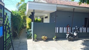 Une maison d’habitation avec un toit en tuiles, une véranda et une entrée fermée par un portail.