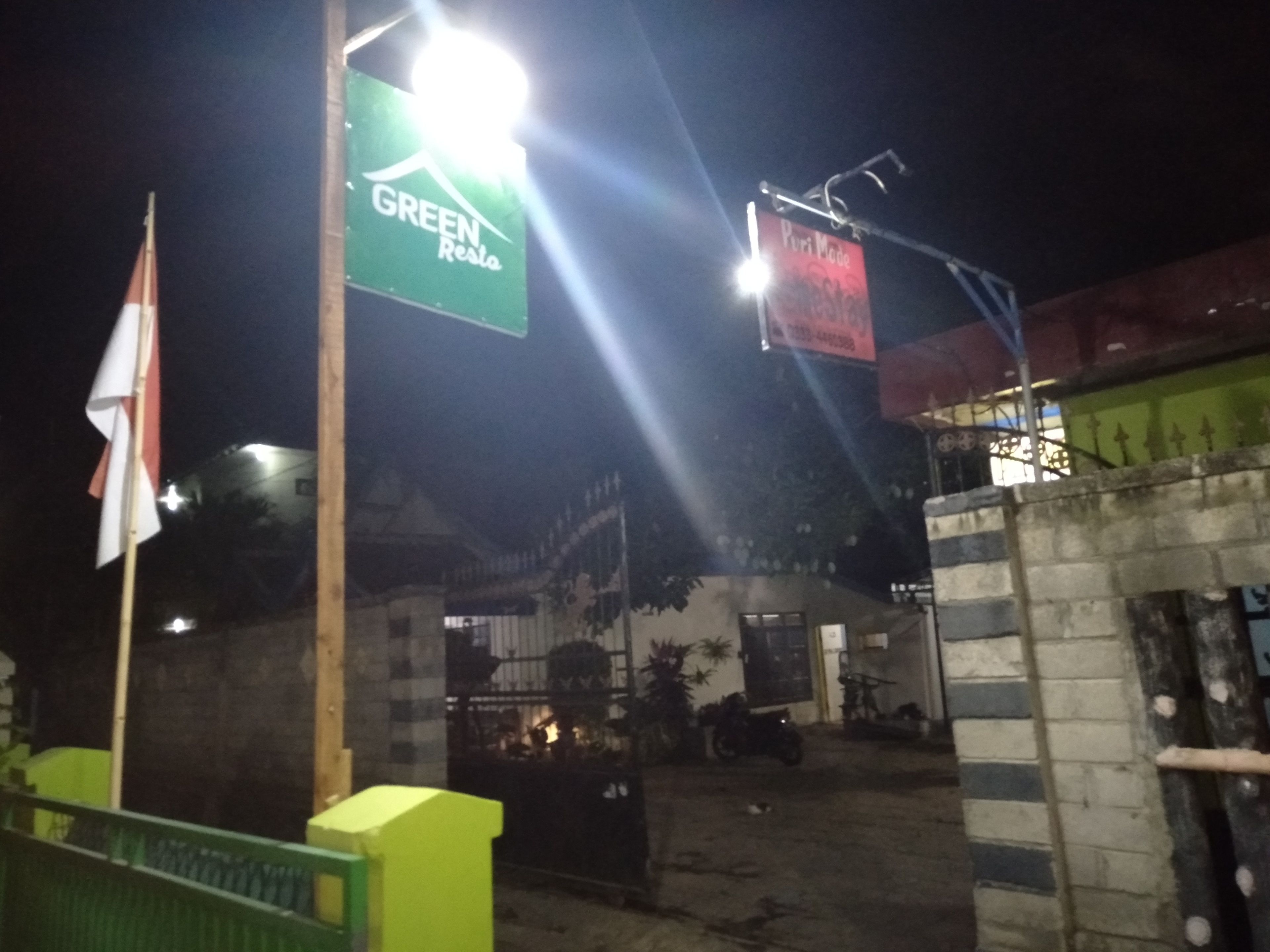 A gated entrance with a sign for 'GREEN RESTA' and another sign for 'Puri Made'.