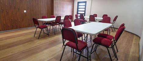 Ein Konferenzraum mit Holzvertäfelung, weißen Tischen und roten Stühlen.