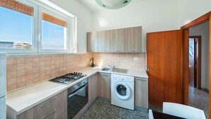 Eine kleine Küche mit Gasherd, Waschmaschine und Spüle.