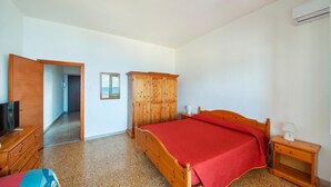 Ein Schlafzimmer mit einem hölzernen Bett, einem Fernseher, einem Kleiderschrank und einem Spiegel.