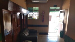 A hallway with a wooden panel wall, a green trash bin, and a fire extinguisher on the wall. - Hotel Regina (Porto Velho)