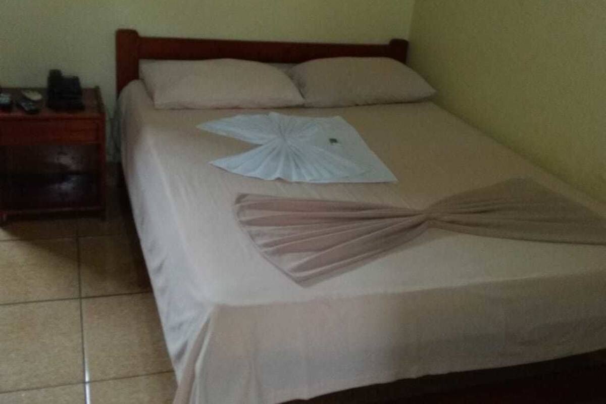 A neatly made bed with a white and pink decorative item on the bedspread.