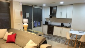 Un espacio habitable compacto con sofá, una pequeña mesa de comedor y una kitchenette.