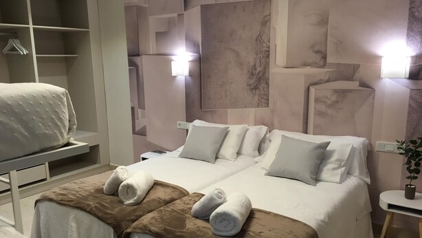 Una habitación de hotel con cama, mesita de noche, armario y una pared con diseños geométricos.