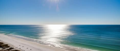 A beach with a clear sky and the sun shining brightly.