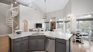 Una cocina moderna con una isla central, muebles oscuros y lavavajillas integrado.