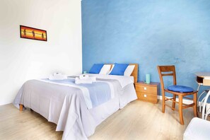 Un dormitorio con cama, una silla, una mesita y una mesilla de noche.