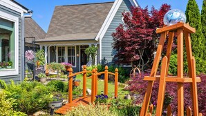 A residential garden with a wooden swing set, a birdhouse, and a variety of plants and flowers. - Clemson Lover's Dream Cottage (Clemson)