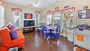 A living room with a sofa, TV, and dining area with chairs and a table. - Clemson Lover's Dream Cottage (Clemson)