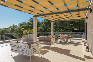 Un espace extérieur aménagé en terrasse, avec un coin salon abrité, une table et des chaises.