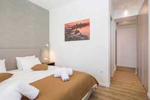 Une chambre d’hôtel avec un lit, une table de chevet, un tableau représentant un coucher de soleil et un plancher en bois.