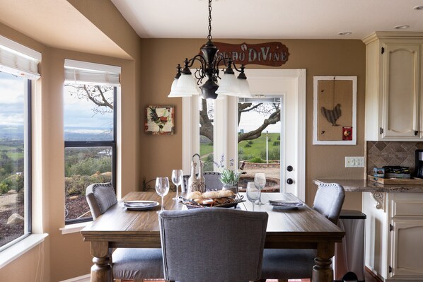 Enjoy meals with a view from this dining area, featuring a table, chairs, and a chandelier.