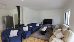 A living room with two blue sofas, a beige sofa, a flat-screen TV, a coffee table, and a fireplace. - Silvanas Retreat (COWES)