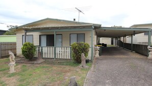 A single-story house with a covered porch, a fenced yard, and a driveway leading to a garage. - Silvanas Retreat (COWES)