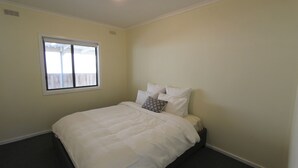 A bedroom with a bed, a window, and a plain wall. - Silvanas Retreat (COWES)