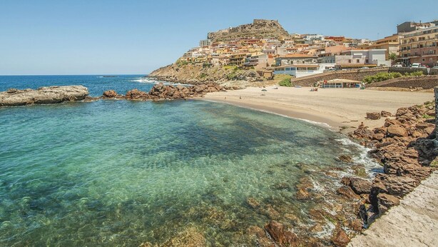 A coastal town with clear waters, rocky shoreline, and buildings on a hillside. - Amazing apartment in Porto Torres with WiFi (Porto Torres)