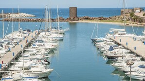 A marina with multiple boats docked, a stone structure, and a clear view of the sea. - Amazing apartment in Porto Torres with WiFi (Porto Torres)