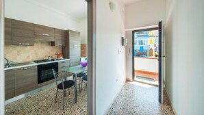 A modern kitchen with a dining area, a view of the outside through a glass door, and a small balcony. - Amazing apartment in Porto Torres with WiFi (Porto Torres)