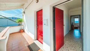 A corridor with red doors leading to a room with a view of the sea. - Amazing apartment in Porto Torres with WiFi (Porto Torres)