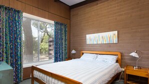 A bedroom with a wooden bed, two bedside tables with lamps, a window with patterned curtains, and a brick wall. - Foreshore Escape Cowes #2 - short walk along the beach to Cowes main street (COWES)