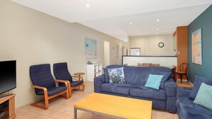 A modern living room with a sofa, two armchairs, a coffee table, and a flat-screen TV. - The Waves Sanctuary Apartment (COWES)