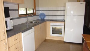 A compact kitchen with a microwave, sink, dishwasher, oven, and refrigerator. - Beachcomber Bliss the perfect family beach house. (SMITHS BEACH)
