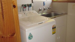 A compact washer and dryer unit with a control panel, a water inlet, and a stainless steel sink. - Beachcomber Bliss the perfect family beach house. (SMITHS BEACH)