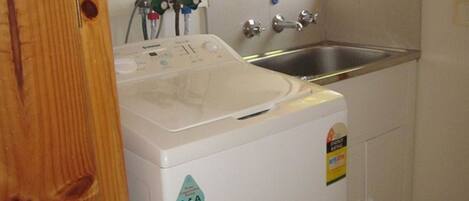 A compact washer and dryer unit with a control panel, a water inlet, and a stainless steel sink.