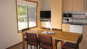 A compact kitchen with a dining table, chairs, a TV, and a microwave. - Beachcomber Bliss the perfect family beach house. (SMITHS BEACH)